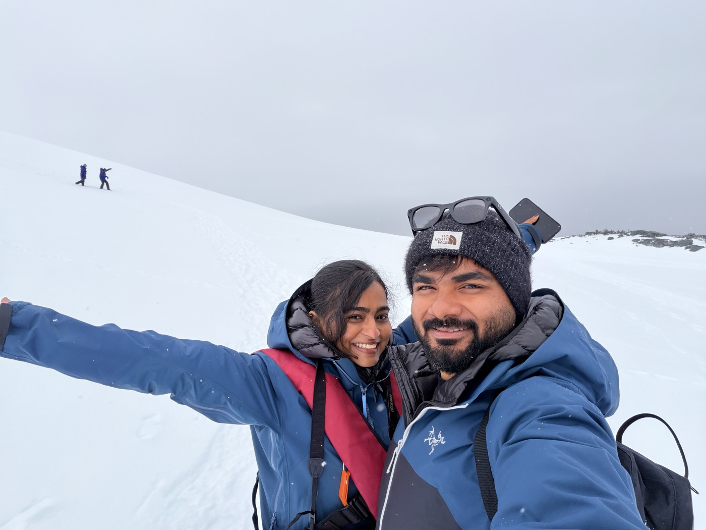 Aditi and Navid bundled up on a snowy slope in Antarctica